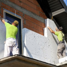 Ouvriers posant des panneaux isolants sur une façade