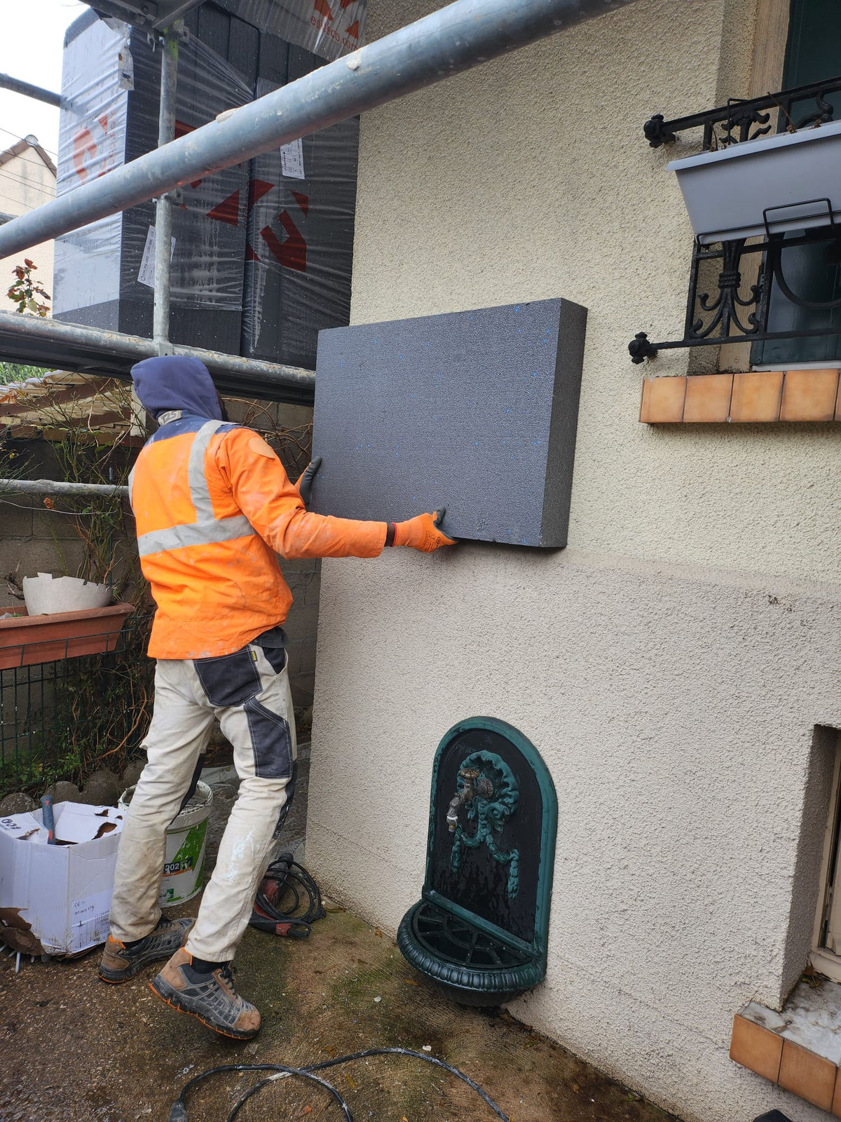 Pose d’un panneau isolant sur une façade, chantier d’isolation par l’extérieur