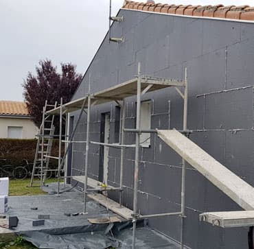 Maison en cours d’isolation thermique par l’extérieur&nbsp;: panneaux isolants posés, échafaudage en place