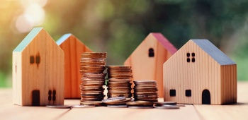 Maisons miniatures en bois et piles de pièces de monnaie