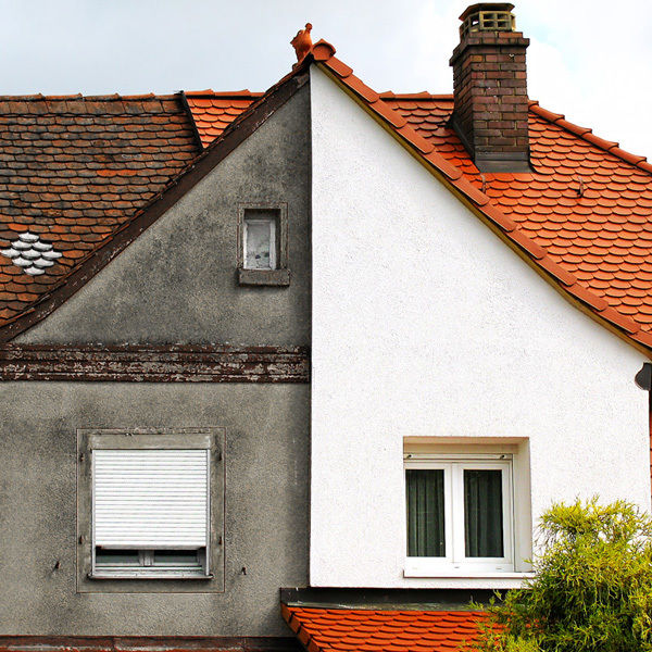 Façade de maison en cours de ravalement, moitié grise et moitié blanche