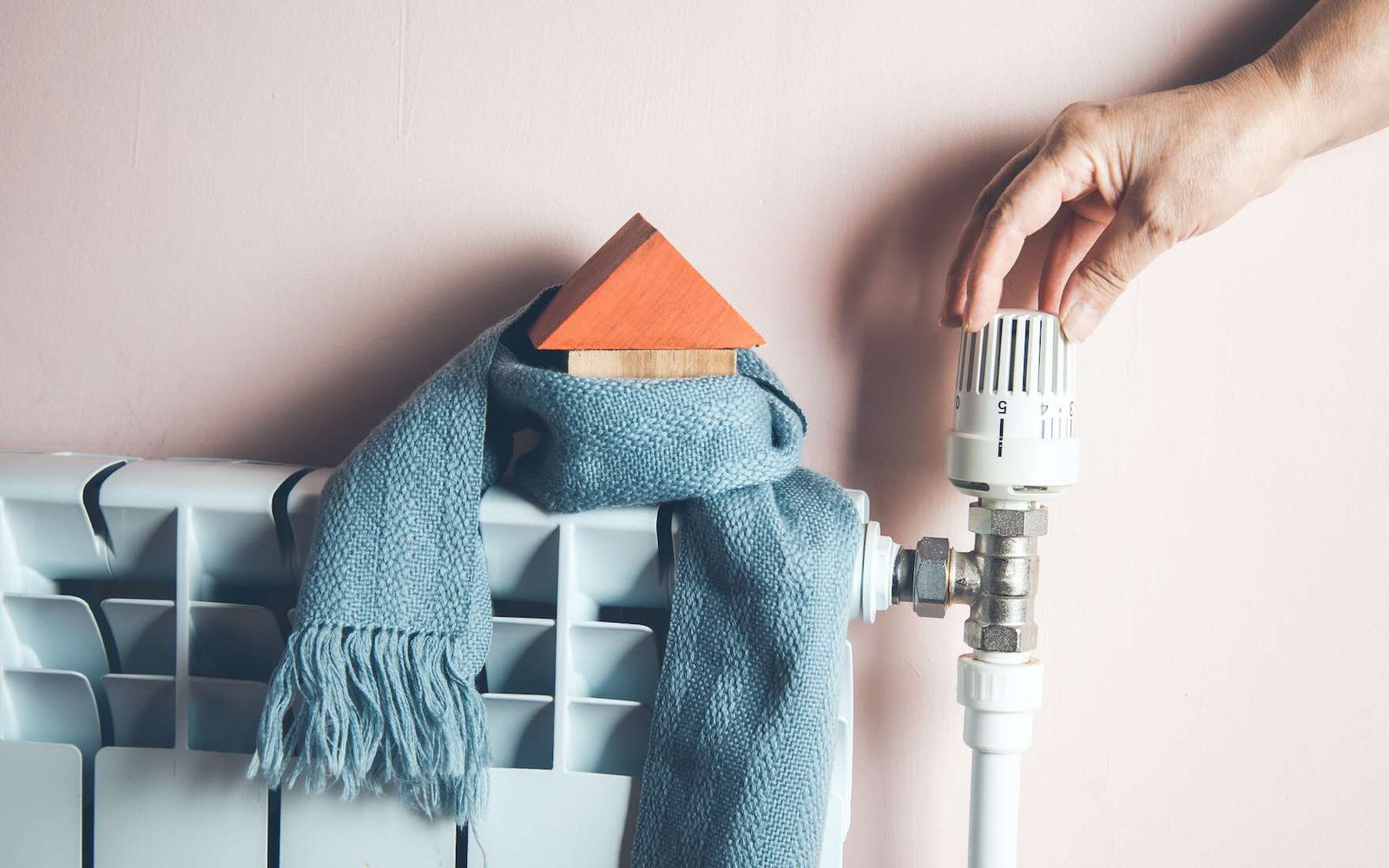 Main réglant le robinet thermostatique d’un radiateur